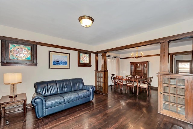 living room featuring a chandelier, ornate columns, baseboards, and wood finished floors