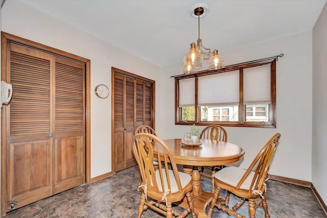 dining room with an inviting chandelier, stone finish floor, and baseboards