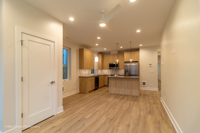 kitchen with pendant lighting, a center island, stainless steel appliances, and light hardwood / wood-style floors