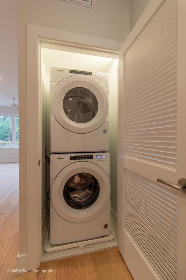 washroom with stacked washer / drying machine and light hardwood / wood-style flooring