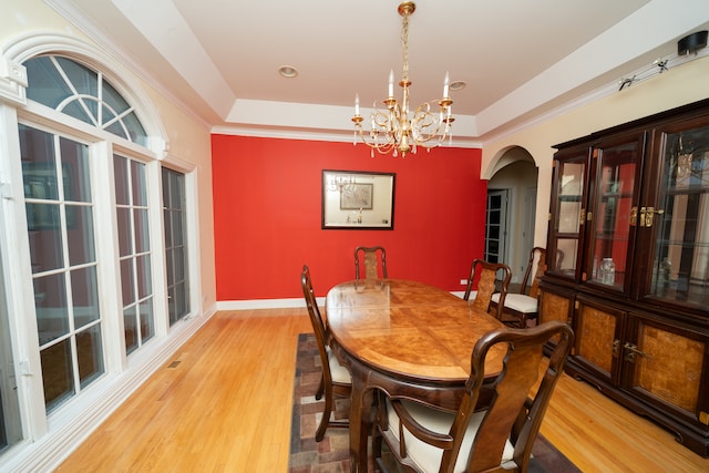 dining room featuring a raised ceiling, wood-type flooring, and an inviting chandelier