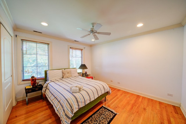 bedroom with ceiling fan, hardwood / wood-style flooring, and crown molding