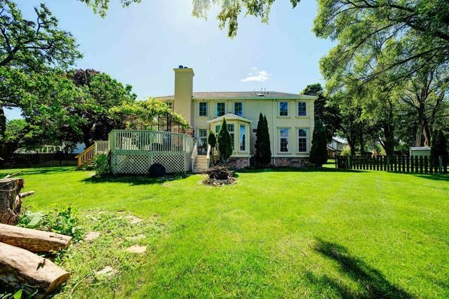 rear view of property with a wooden deck and a lawn