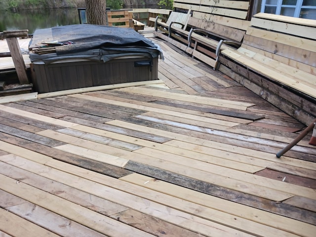 wooden terrace featuring a hot tub and a water view