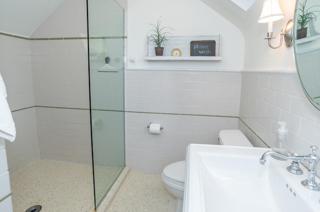 bathroom with a tile shower, sink, tile walls, and toilet