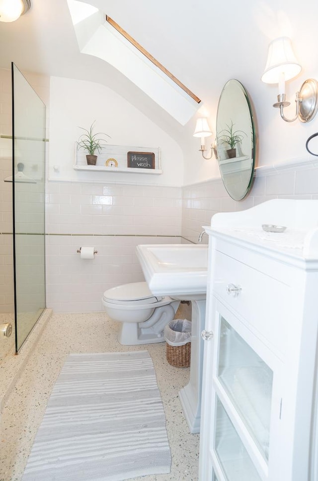 bathroom featuring tile walls, toilet, and a tile shower