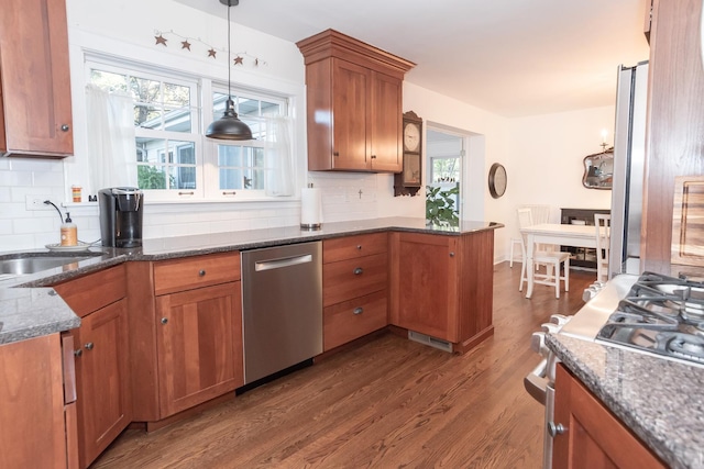 kitchen with pendant lighting, sink, decorative backsplash, and stainless steel appliances