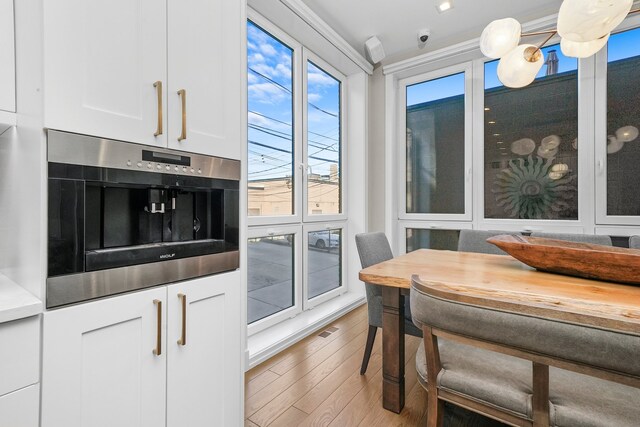 kitchen with wooden counters, stainless steel oven, hardwood / wood-style flooring, ornamental molding, and white cabinetry