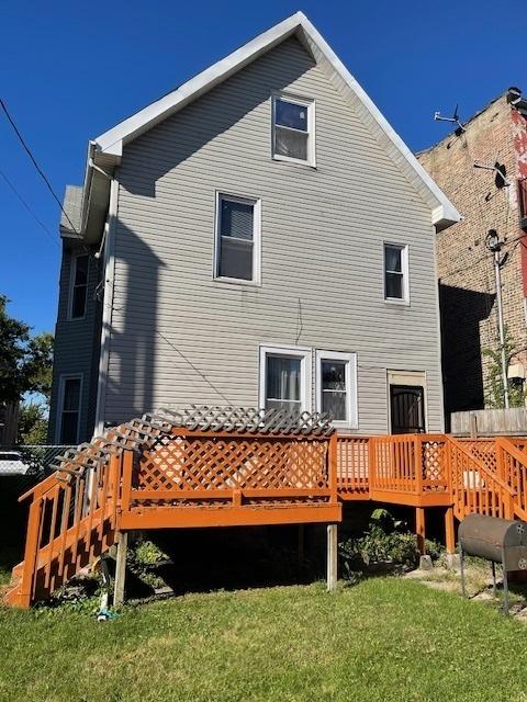 back of property featuring a lawn, a wooden deck, and heating fuel