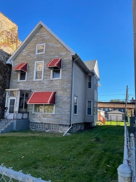 back of property featuring fence and a yard