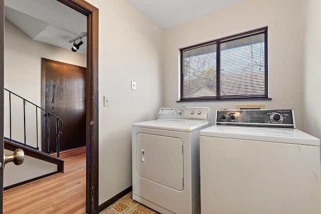 clothes washing area with track lighting, light hardwood / wood-style flooring, and washer and dryer