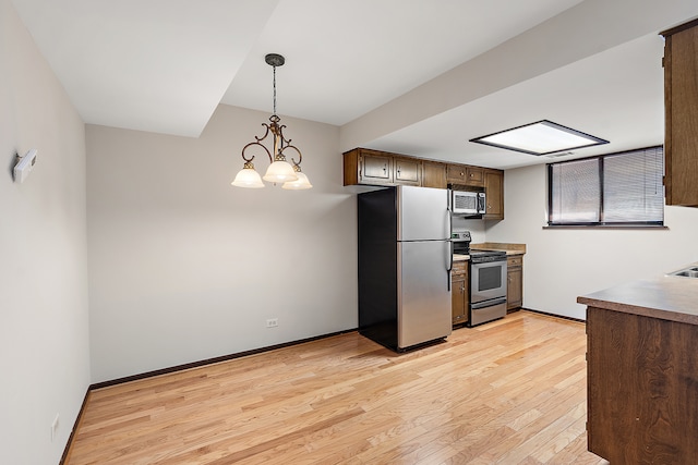 kitchen featuring an inviting chandelier, appliances with stainless steel finishes, hanging light fixtures, and light wood-type flooring