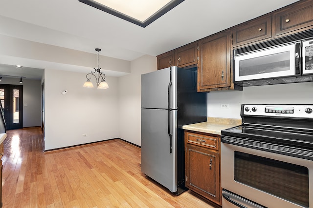 kitchen featuring appliances with stainless steel finishes, light hardwood / wood-style flooring, decorative light fixtures, and an inviting chandelier