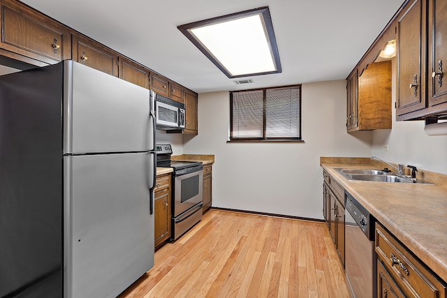 kitchen with sink, stainless steel appliances, and light hardwood / wood-style floors