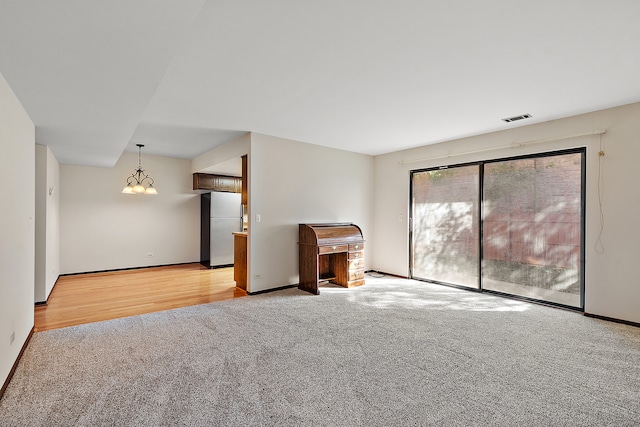 empty room with an inviting chandelier and light wood-type flooring