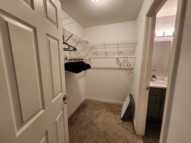 spacious closet featuring sink and dark colored carpet