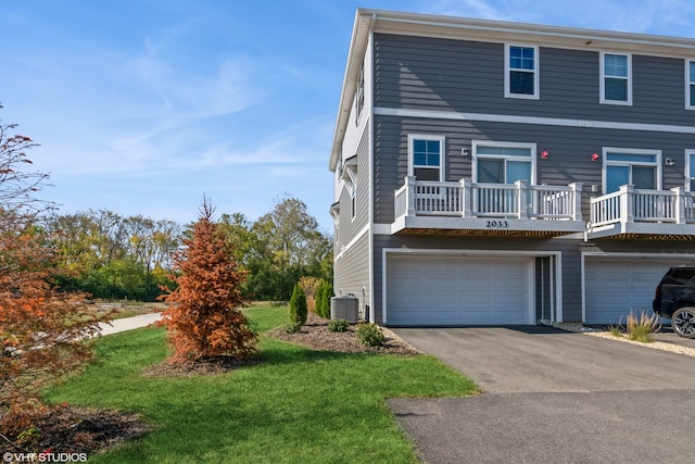 view of front of home with central AC, a garage, and a front lawn