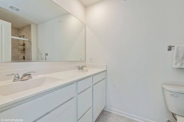 bathroom featuring toilet, vanity, tile patterned floors, and a shower with door