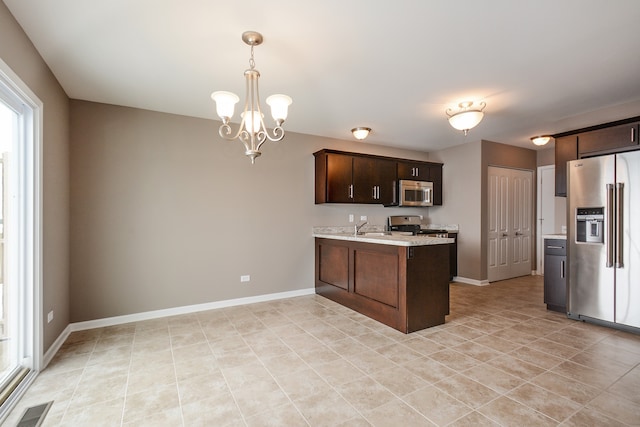 kitchen featuring kitchen peninsula, dark brown cabinets, appliances with stainless steel finishes, an inviting chandelier, and pendant lighting