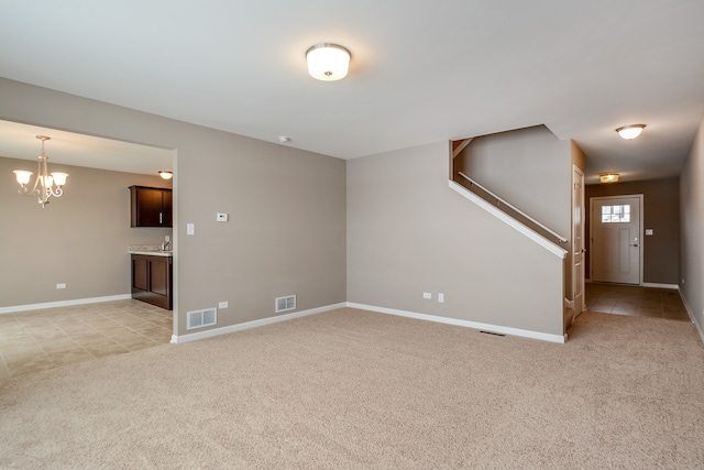 unfurnished living room featuring sink, a chandelier, and light carpet