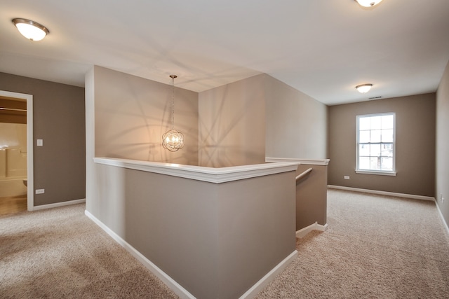 hall featuring light colored carpet and an inviting chandelier