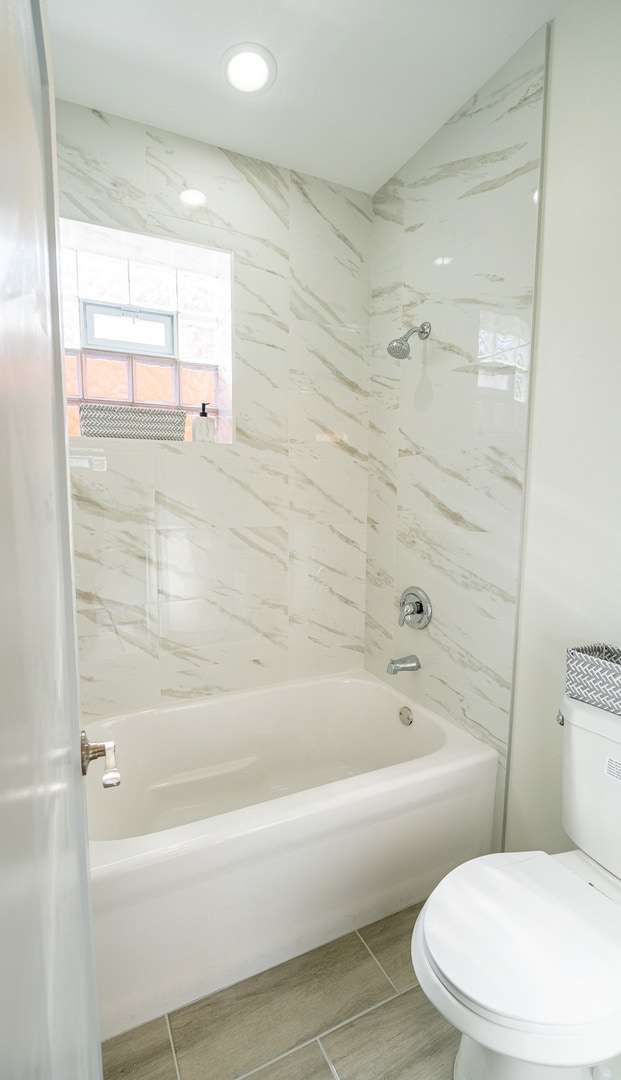 bathroom featuring toilet and tiled shower / bath