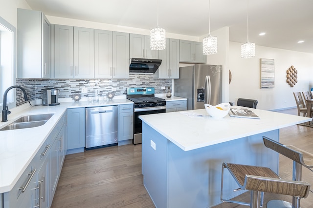 kitchen with sink, a center island, hardwood / wood-style floors, a kitchen breakfast bar, and stainless steel appliances