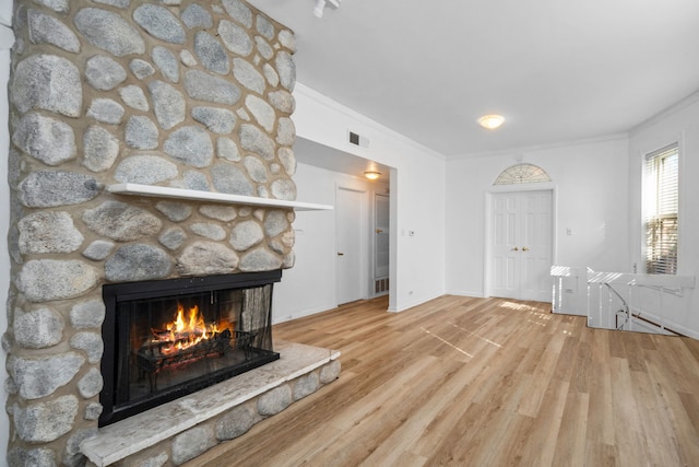 unfurnished living room with crown molding, a fireplace, and wood-type flooring