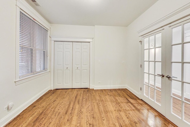 unfurnished bedroom with french doors, light hardwood / wood-style flooring, and a closet