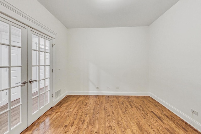 spare room featuring french doors and light wood-type flooring