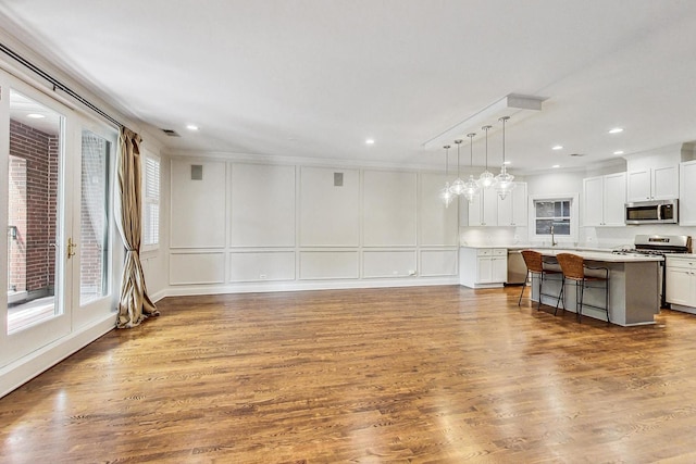 living room featuring ornamental molding, sink, and wood-type flooring