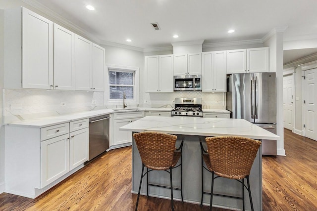 kitchen featuring stainless steel appliances, wood-type flooring, a center island, and white cabinets