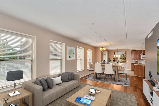 living room featuring a wealth of natural light, dark wood-type flooring, a textured ceiling, and an inviting chandelier