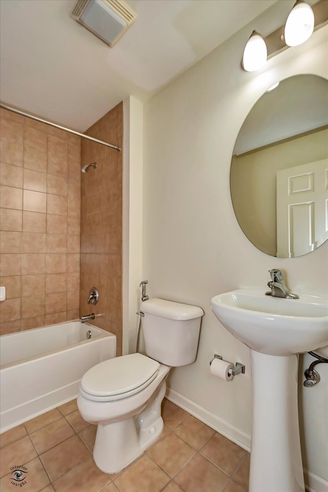 full bathroom with toilet, tiled shower / bath combo, sink, and tile patterned floors