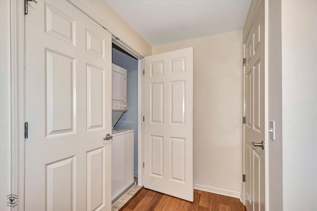 hall featuring wood-type flooring and stacked washer and clothes dryer