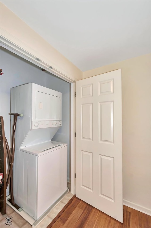 clothes washing area with stacked washer / dryer and light hardwood / wood-style flooring