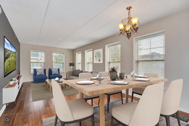 dining room with an inviting chandelier, a healthy amount of sunlight, and dark hardwood / wood-style flooring