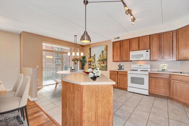 kitchen with a kitchen island, decorative light fixtures, rail lighting, light tile patterned floors, and white appliances