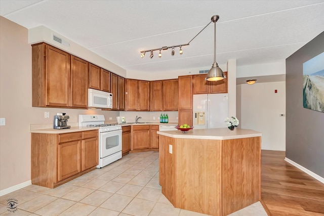 kitchen with white appliances, light hardwood / wood-style floors, a center island, and pendant lighting