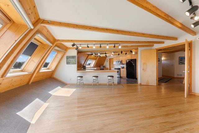 unfurnished living room featuring vaulted ceiling with beams and light wood-type flooring