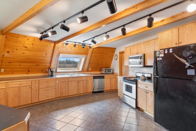 kitchen featuring wood walls, stainless steel appliances, and light brown cabinetry