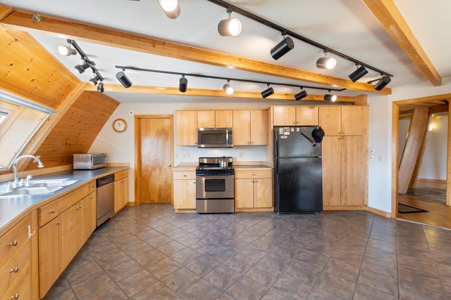 kitchen with light brown cabinetry, appliances with stainless steel finishes, sink, and dark tile patterned floors