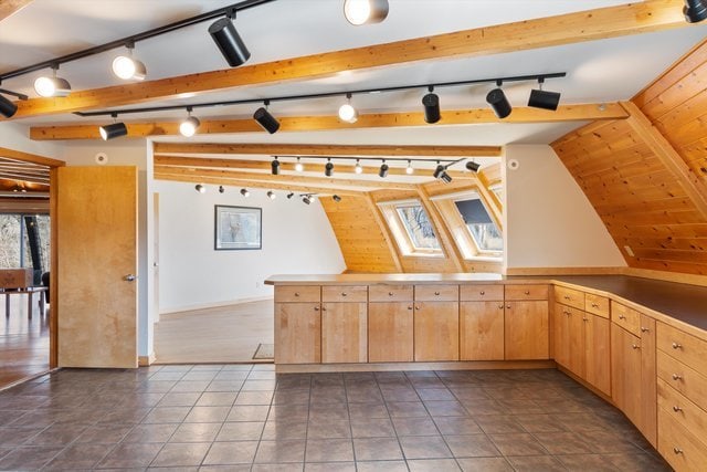 kitchen with vaulted ceiling with beams, light brown cabinets, and dark tile patterned flooring