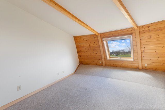 additional living space featuring wood walls, carpet floors, and vaulted ceiling with beams