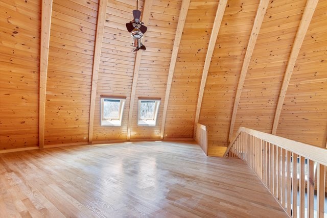 additional living space featuring wood ceiling, wood-type flooring, vaulted ceiling with skylight, and wooden walls