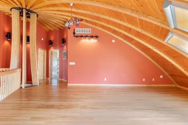 unfurnished living room with vaulted ceiling with beams, hardwood / wood-style floors, and wooden ceiling