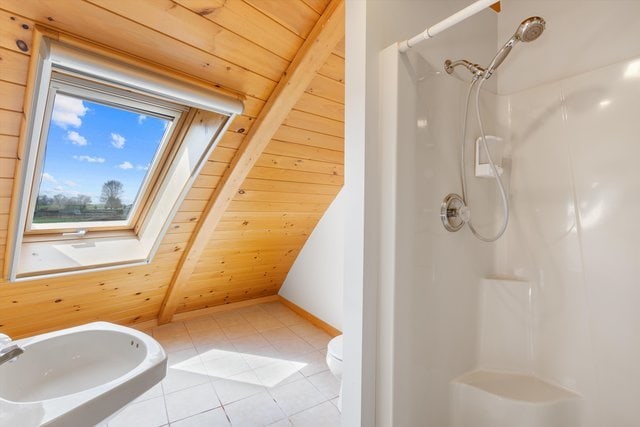 bathroom featuring tile patterned floors, toilet, wooden ceiling, a shower, and lofted ceiling with skylight