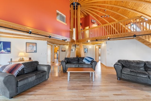 living room with beamed ceiling, light wood-type flooring, high vaulted ceiling, and wooden ceiling