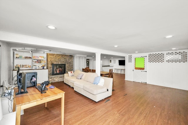 living room with built in shelves, a fireplace, and hardwood / wood-style flooring