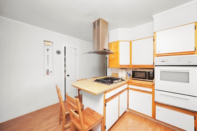 kitchen with white cabinetry, wall chimney range hood, appliances with stainless steel finishes, and light wood-type flooring